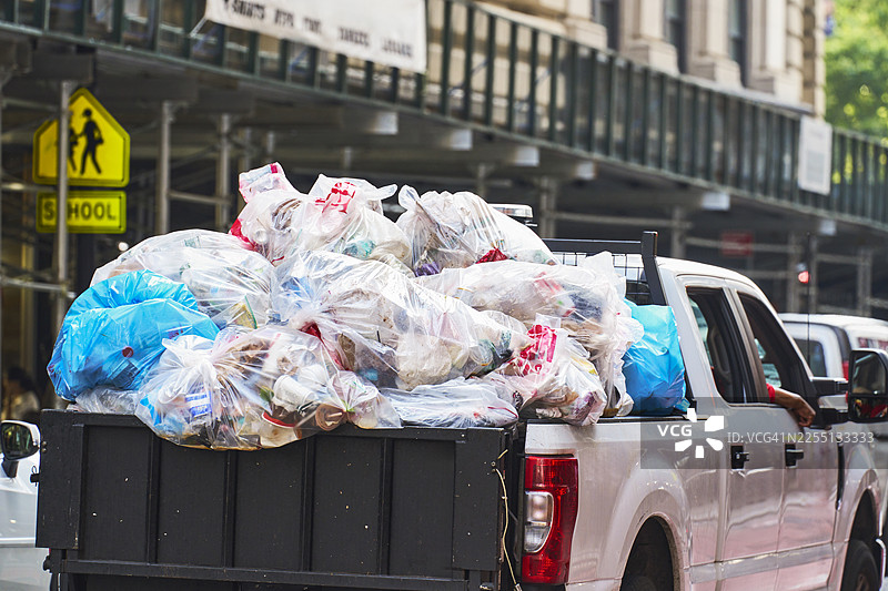 装满垃圾袋的皮卡车在城市街道上造成污染图片素材
