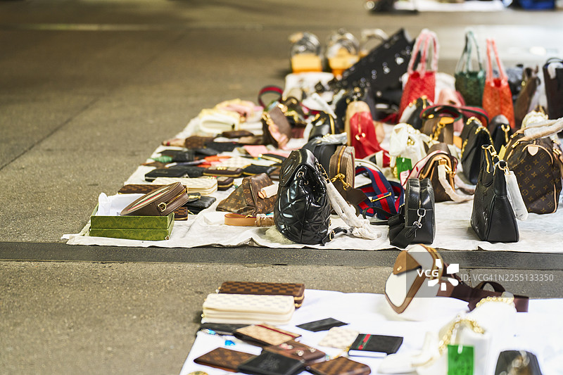 街头市场摊位上售卖的假冒奢侈品手袋和钱包图片素材