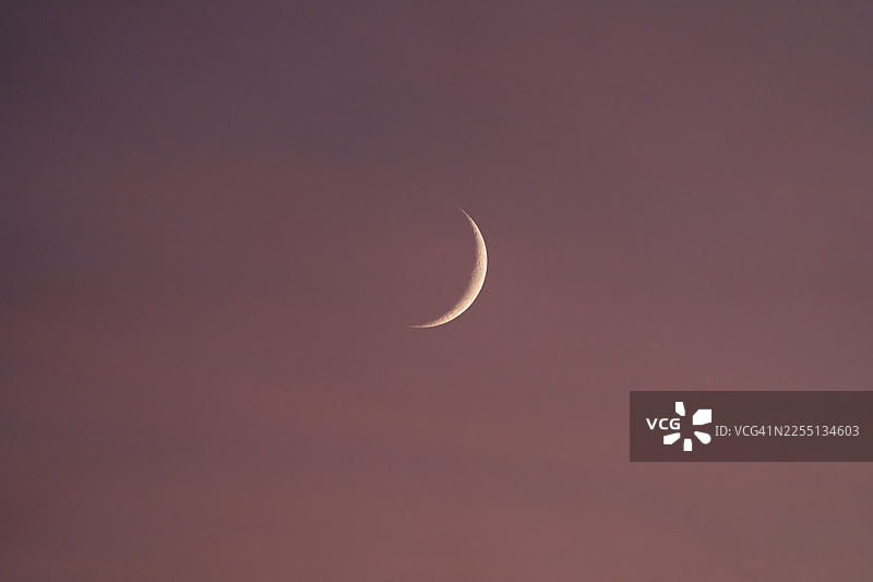 彩色的日落天空中弯弯的月亮。图片素材