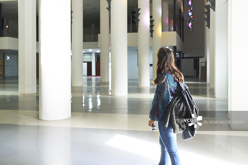年轻女子在带有柱子的现代建筑中探索图片素材