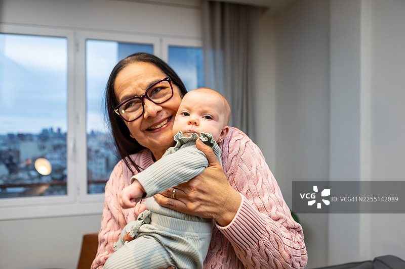 祖母抱着小孙女在家拜访家人图片素材