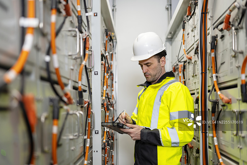 电气工程师或技术人员在电池储能控制室对电池连接进行例行检查，这对安全和性能至关重要。图片素材
