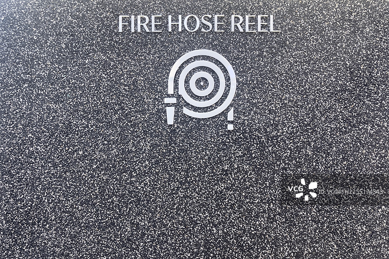 带有白色水龙带图标和文字的消防水龙带卷盘标志，背景为斑驳的灰色。图片素材