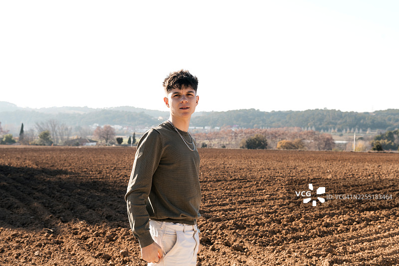 年轻男子站在晴朗天空下的犁地里图片素材