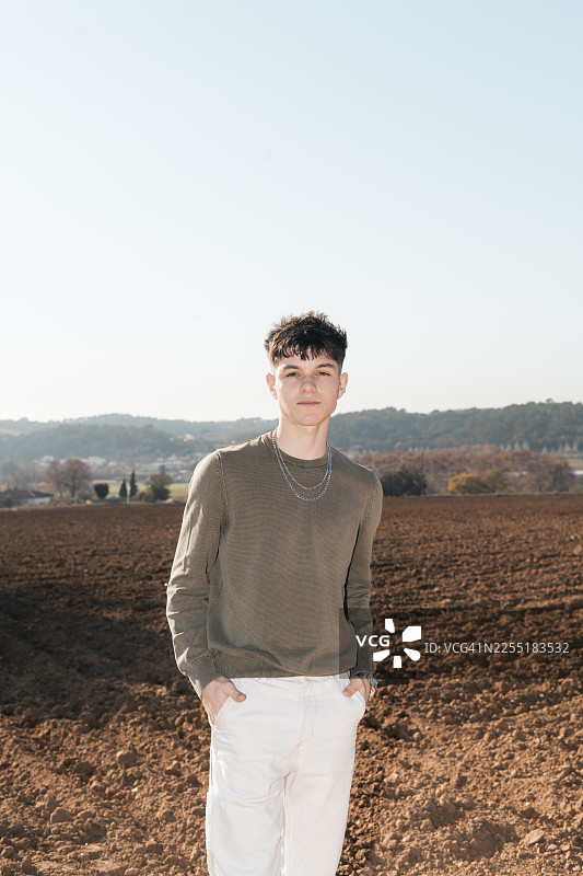 年轻男子站在晴朗天空下的犁地里图片素材