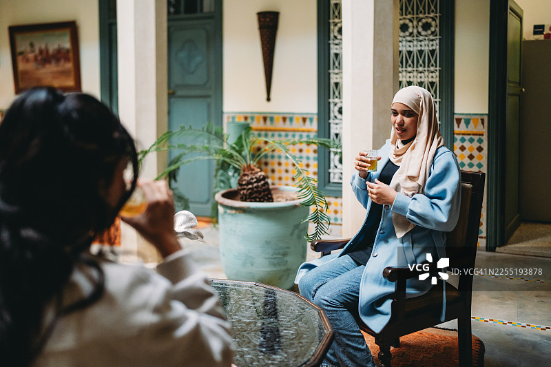 两位年轻的穆斯林女性在传统的摩洛哥庭院里享用茶点图片素材
