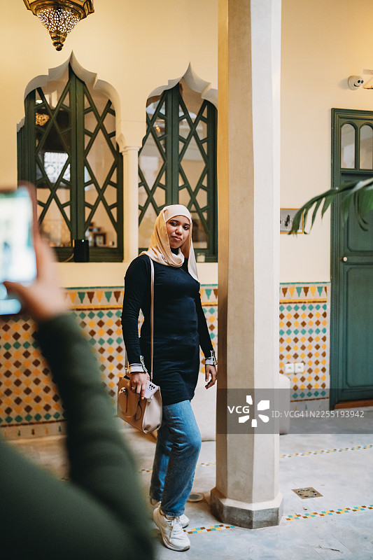 一位穆斯林女性在摩洛哥庭院旅馆用手机拍照图片素材