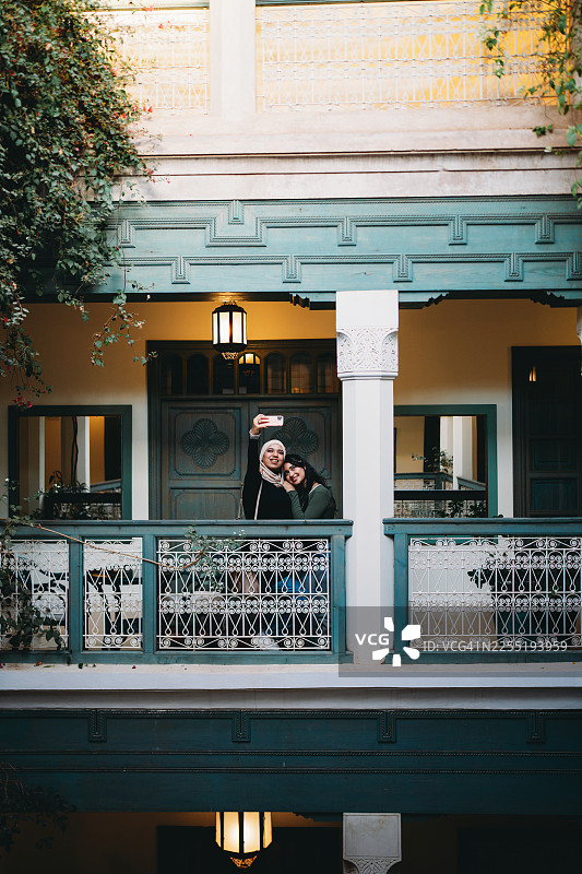 两位年轻成年女性在庭院阳台上自拍图片素材