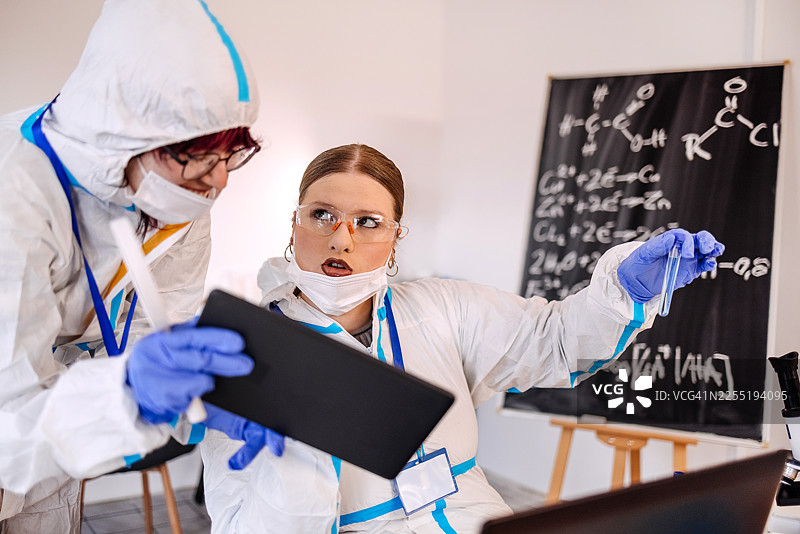 年轻的科学家们在实验室里合作，使用数字平板和笔记本电脑进行研究图片素材