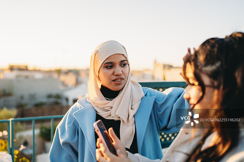 日落时分，年轻的穆斯林女性朋友们在屋顶上交谈图片素材