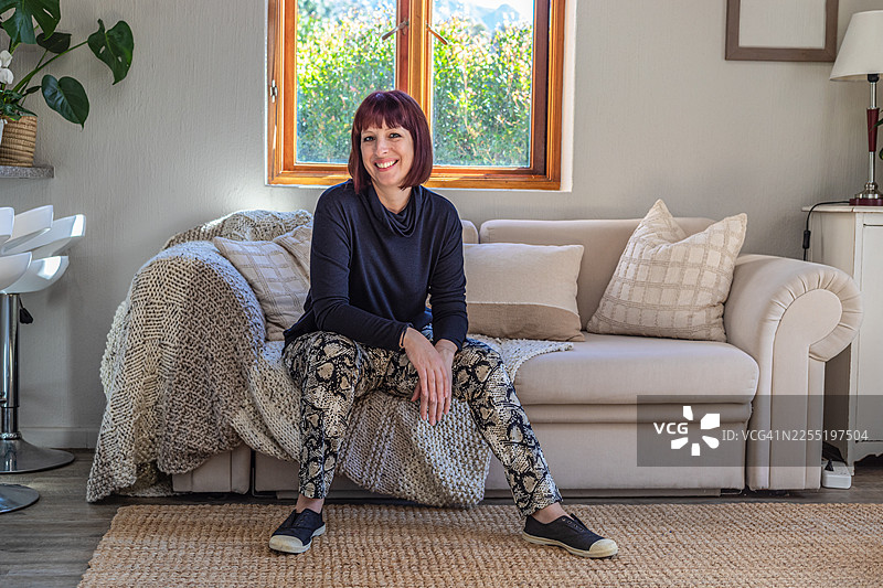 女人坐在沙发上，胳膊肘搭在腿上图片素材