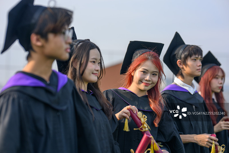 年轻女毕业生在户外手持毕业文凭图片素材