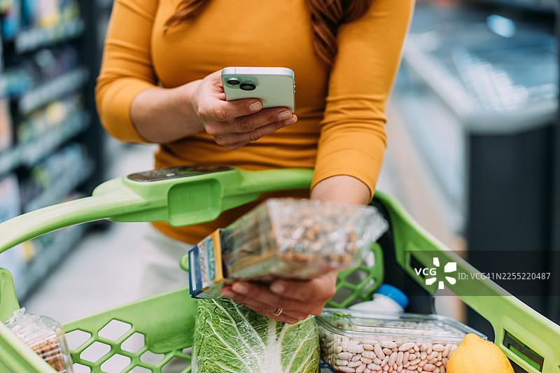 女性在超市购物时扫描商品上的二维码图片素材