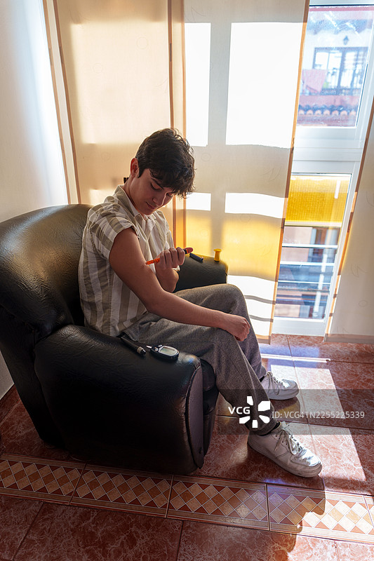 年轻男子在家中注射胰岛素，管理糖尿病图片素材