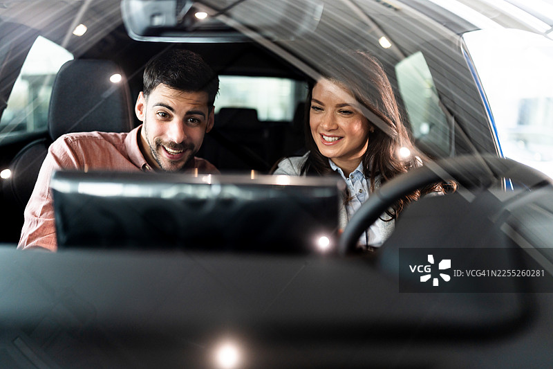 一对快乐的年轻夫妇在经销商处购买新车图片素材