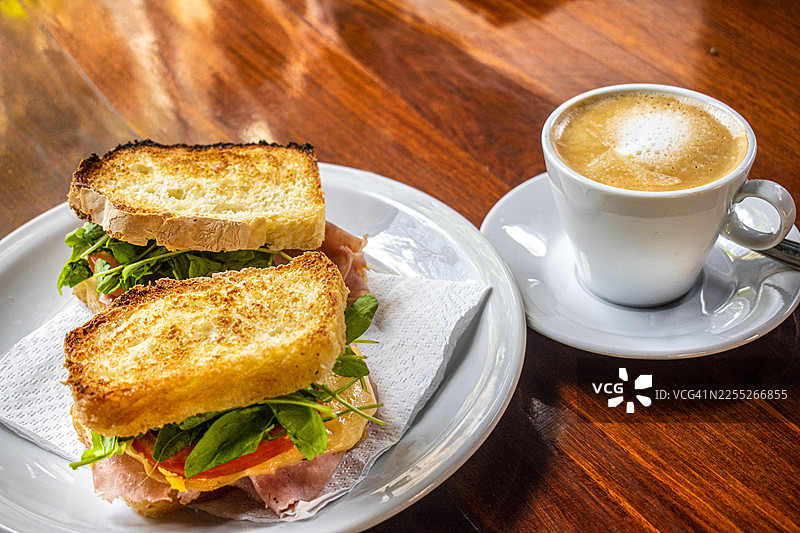 火腿、奶酪和蔬菜三明治，配一杯加奶的咖啡（拿铁）。图片素材