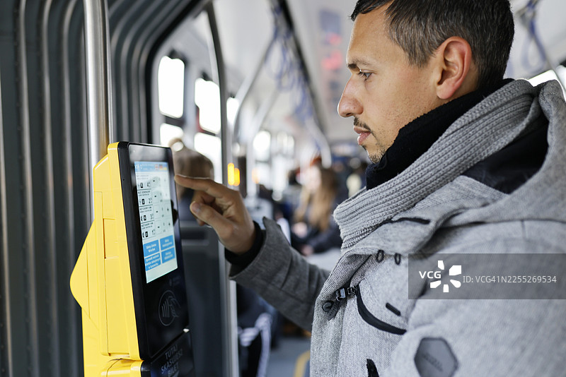 波兰弗罗茨瓦夫，一名男子在电车售票机屏幕上选择车票类型的侧面视图图片素材