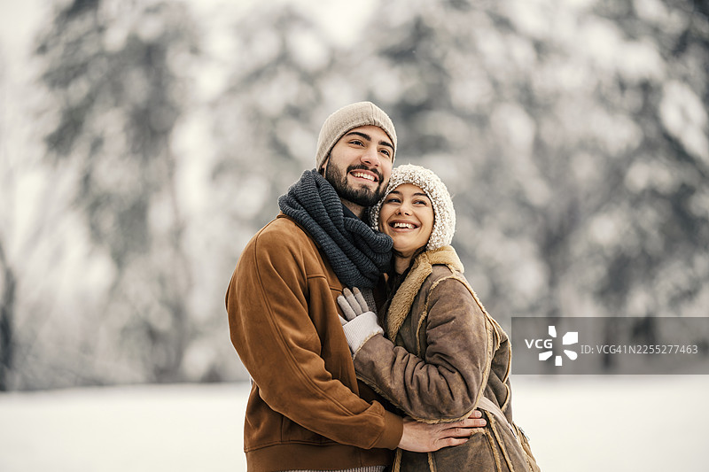 一对幸福的情侣在户外的冬日雪景中拥抱图片素材