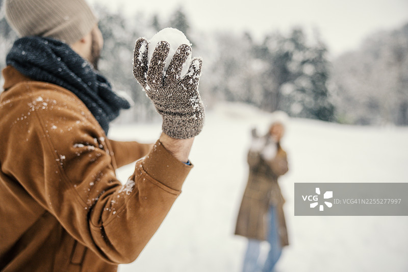 一对情侣在冬日森林里嬉戏打雪仗，玩得不亦乐乎图片素材