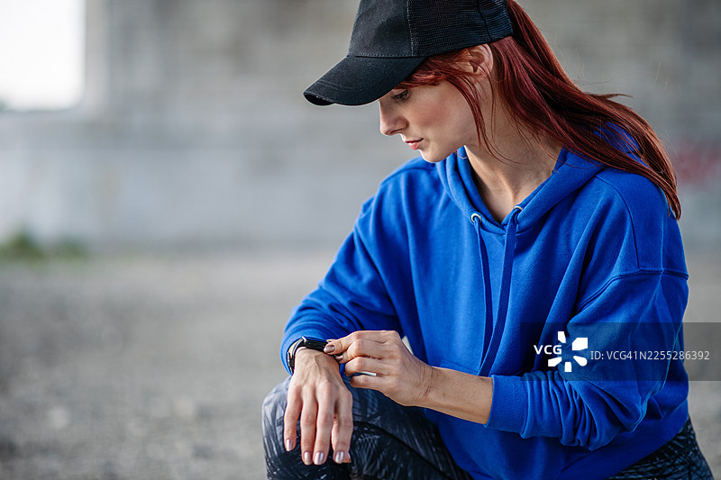 运动中的女性在智能手表上查看训练进度。图片素材