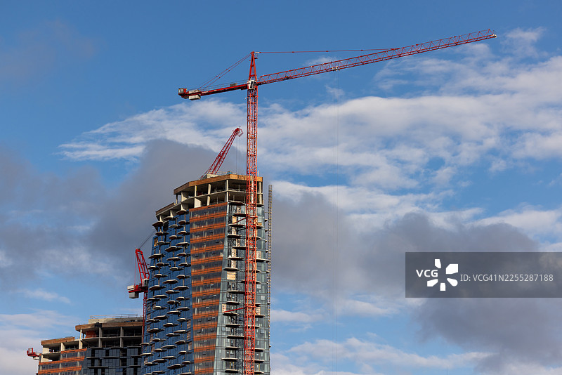 蓝天下的高层建筑上方的建筑起重机图片素材
