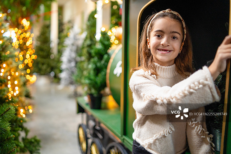 小女孩在圣诞节游乐场或市集的旋转木马火车上图片素材