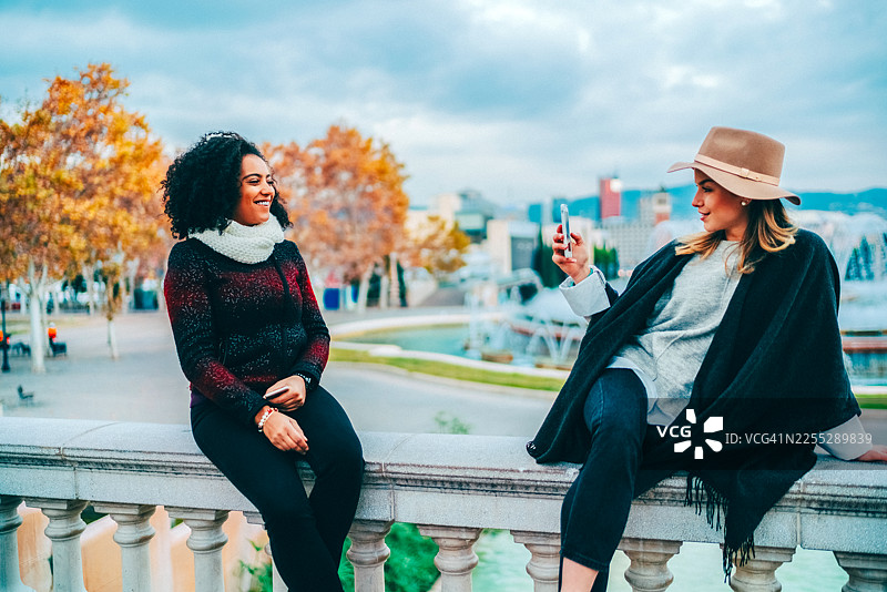 两位女士在巴塞罗那的喷泉旁拍照留念图片素材