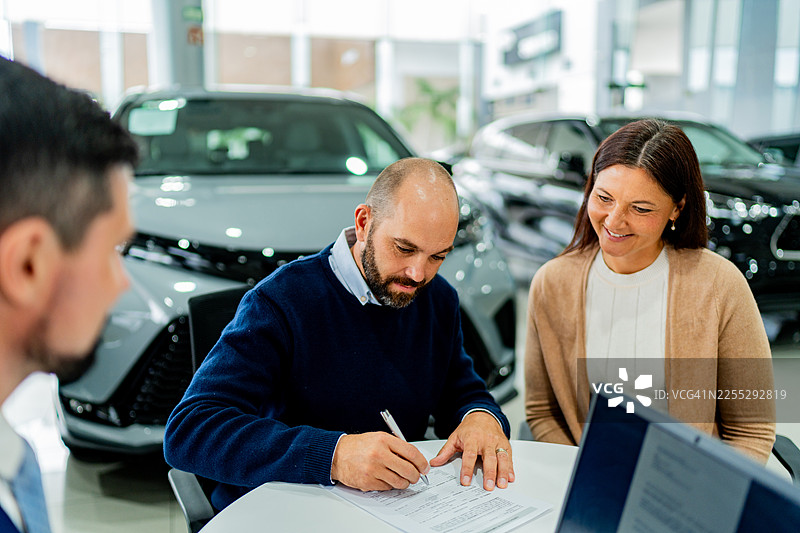情侣在汽车经销商处签署文件图片素材
