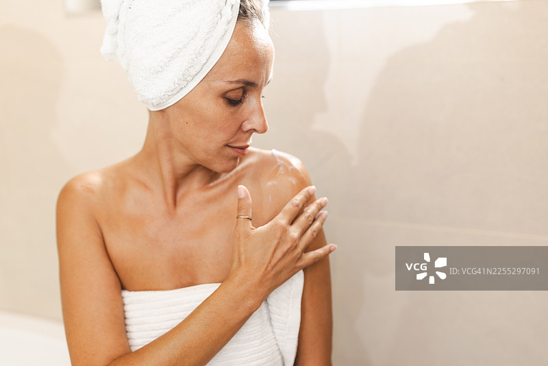 洗澡后自信的女人在家穿着浴袍放松，享受自我护理时光和护肤流程图片素材