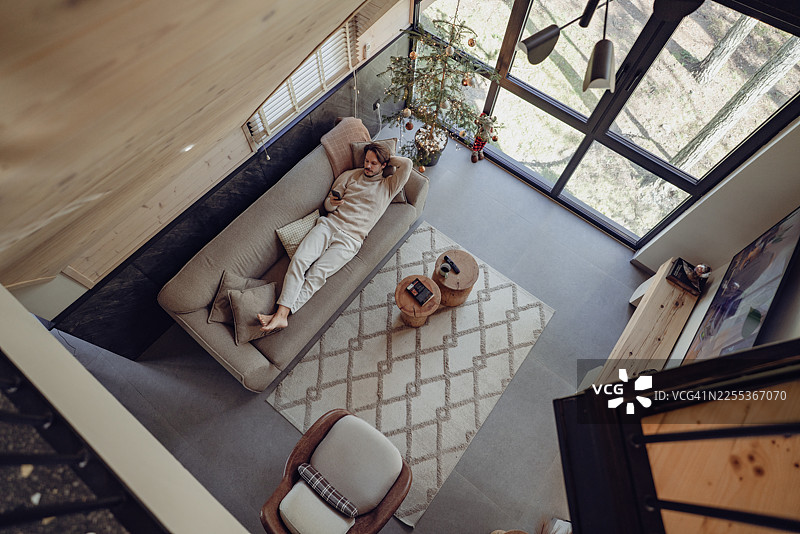 年轻人躺在沙发上玩手机图片素材