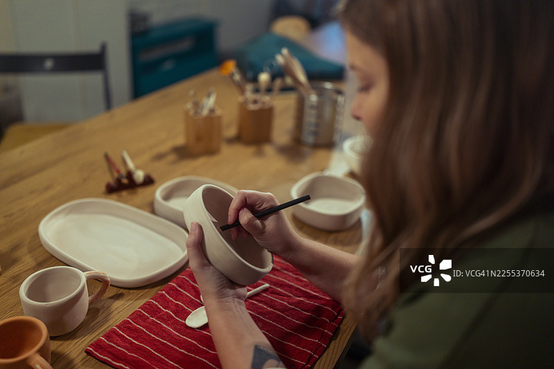陶艺工作室里，陶艺师的手正在给手工碗上色图片素材