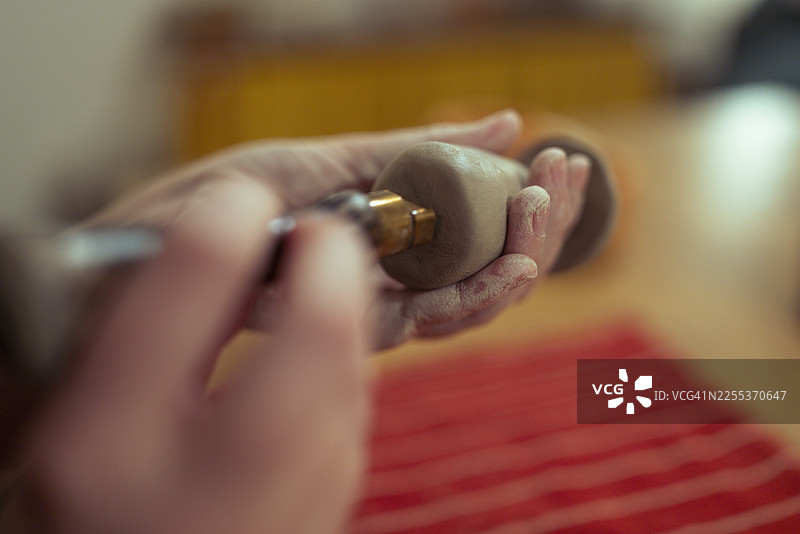 特写聚焦于工匠的手，他们正按压手中制作的小型陶艺品的底部或内部图片素材