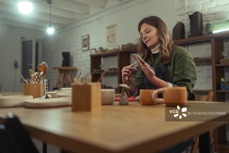 专注的女性工匠在陶艺工作室用工具打磨陶土盘图片素材