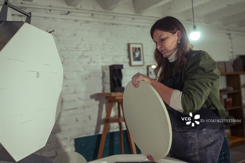 陶艺师在窑炉内小心地摆放未完成的陶器图片素材