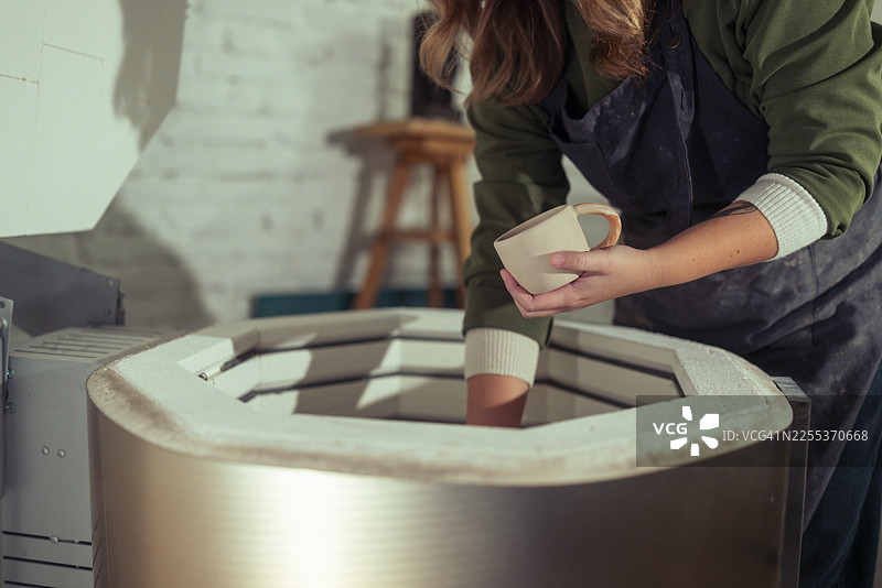 陶艺师将陶瓷杯放入窑中图片素材