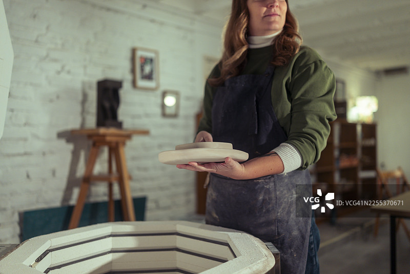 女陶艺师在工作室准备将陶瓷作品放入电窑图片素材