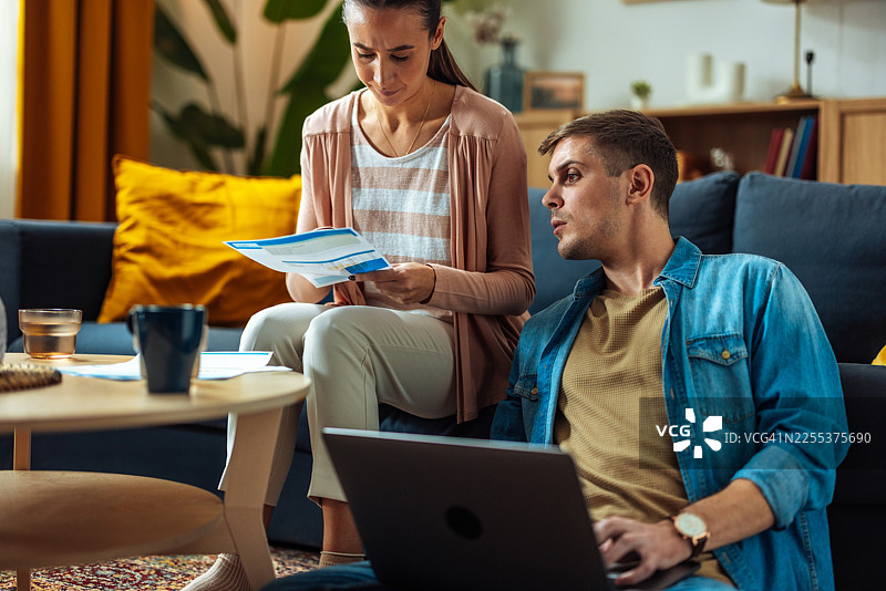 两个人居家协作，在舒适的客厅里用笔记本电脑查阅文件图片素材