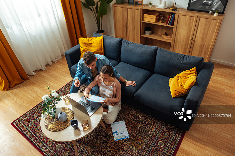 一对情侣在舒适的客厅里一起使用笔记本电脑和处理文件图片素材