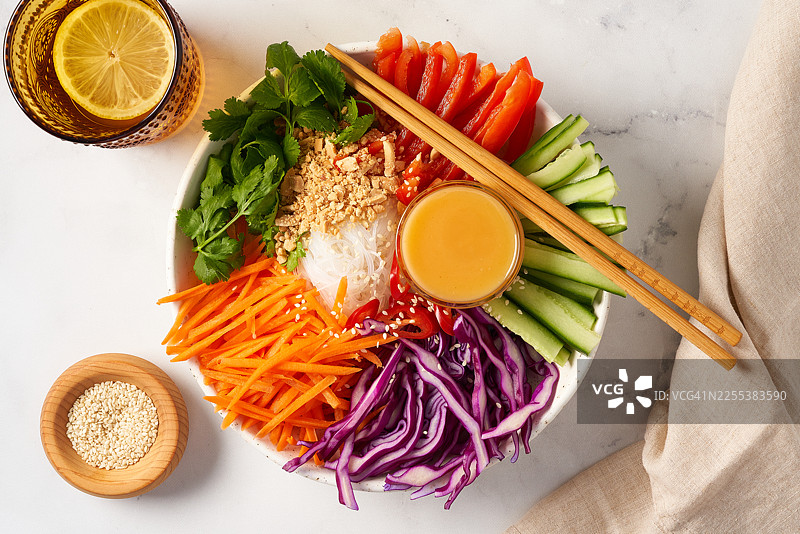 色彩缤纷的亚洲米粉沙拉碗，配有新鲜蔬菜和花生酱。健康的纯素餐食准备。图片素材
