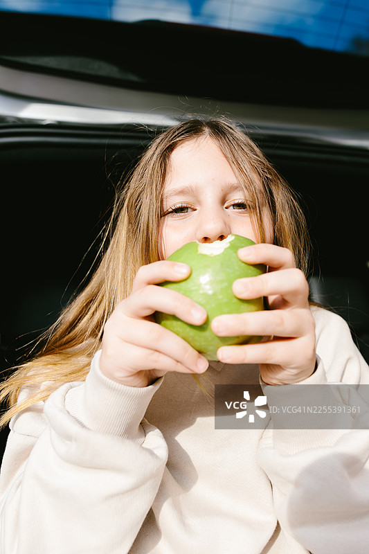 孩子在家庭公路旅行休息时吃青苹果图片素材