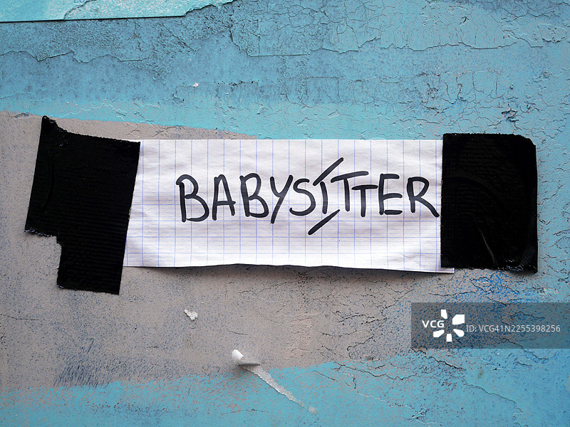 保姆，手写在一张贴在饱经风霜的蓝色墙壁上的纸上图片素材