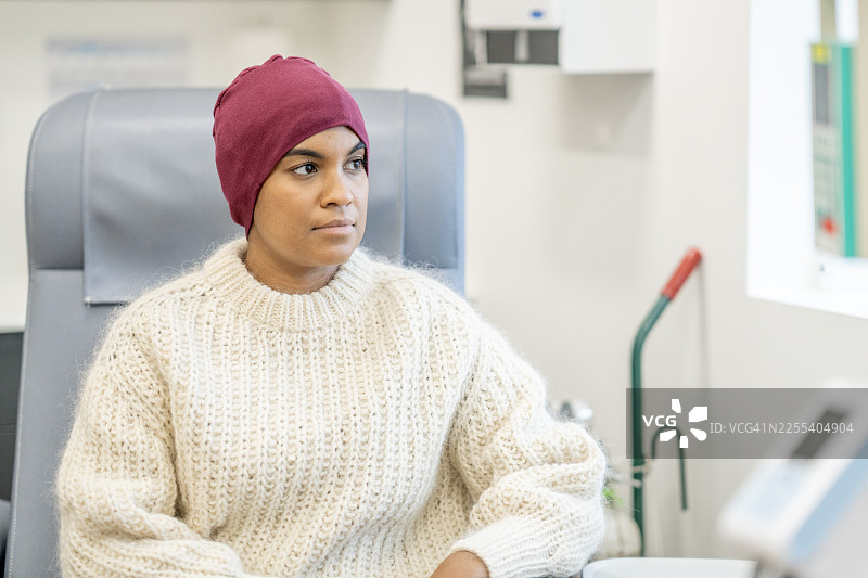 一位戴着酒红色头巾的黑人女患者在诊所接受治疗时坐在医疗椅上图片素材