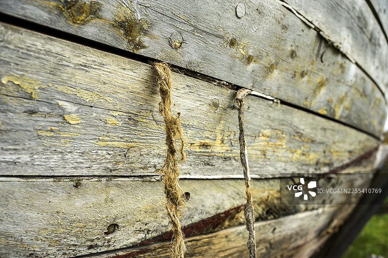 特写镜头,一艘旧渔船上饱经风霜的木板,船板间的麻绳清晰可见,位于挪威芬马克郡的韦斯特雅各布塞尔夫。图片素材