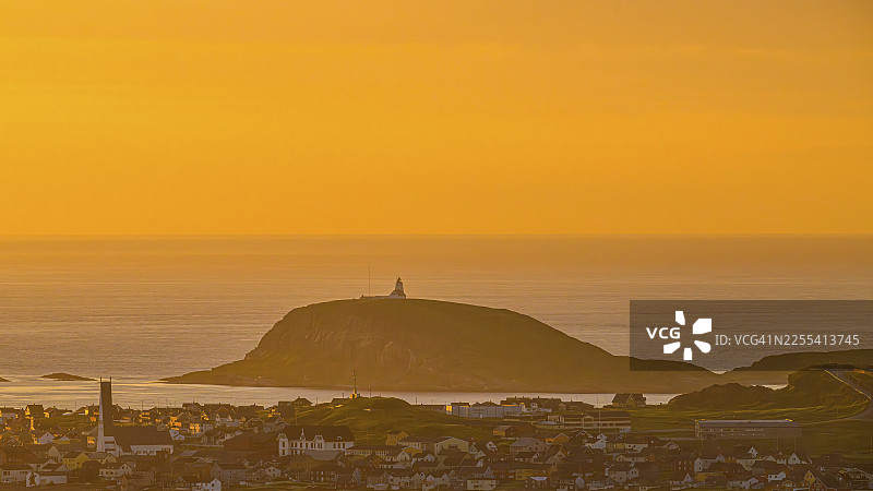 从多门山(Mount Domen)远眺瓦尔德市(Vardø),背景是拥有灯塔的霍尔诺亚岛(Hornoya),海上日落时金色的天空和宁静的氛围,位于挪威芬马克郡的基贝格(Kiberg)。图片素材