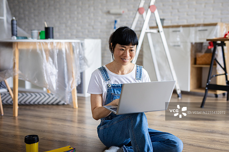 女子在翻新期间用笔记本电脑搜索室内设计创意图片素材