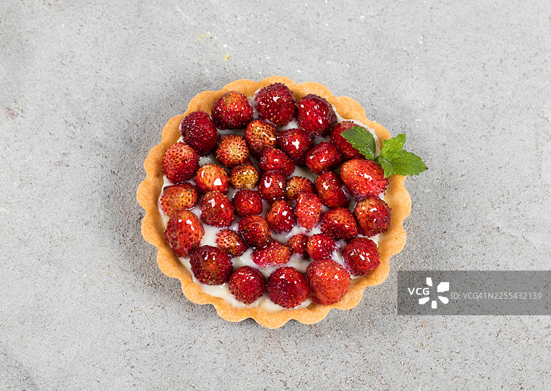 草莓挞。配蛋奶冻，配薄荷。浅灰色背景。俯视角度图片素材