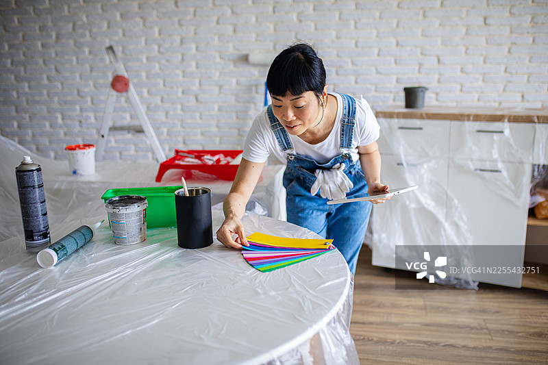 女性使用数字室内设计应用程序选择油漆颜色图片素材