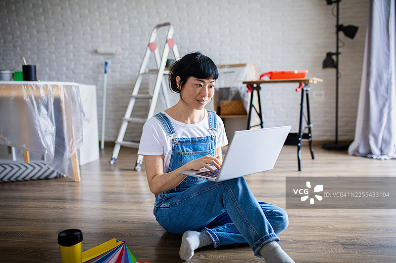 女子在装修期间用笔记本电脑搜索室内设计灵感图片素材
