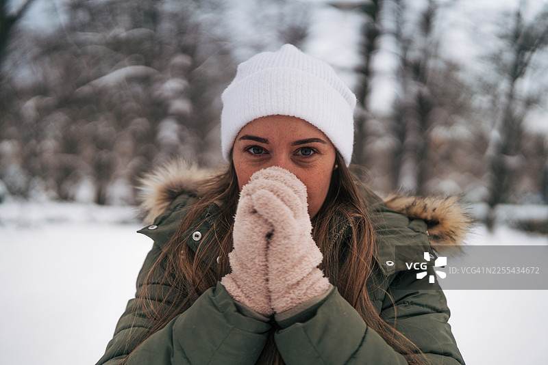 年轻女子在冬天的雪中暖手图片素材