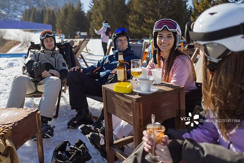 朋友们在阳光明媚的滑雪度假村咖啡馆享用饮品并交谈图片素材